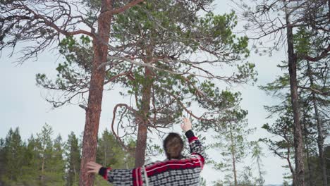 norwegian guy gathering some dried tree branches for bonfire in forest