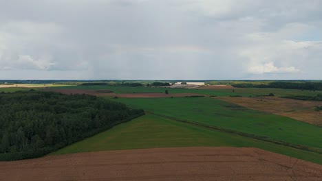 el arco iris sobre el campo verde después de la tormenta con lluvia, durante el otoño, vista aérea bajo nubes pesadas antes de la tempestad