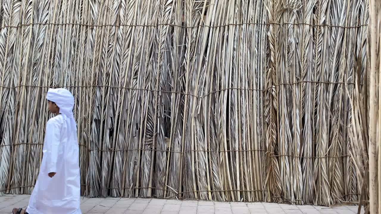 niño de los emiratos arabes unidos con vestido árabe tradicional kandura caminando.