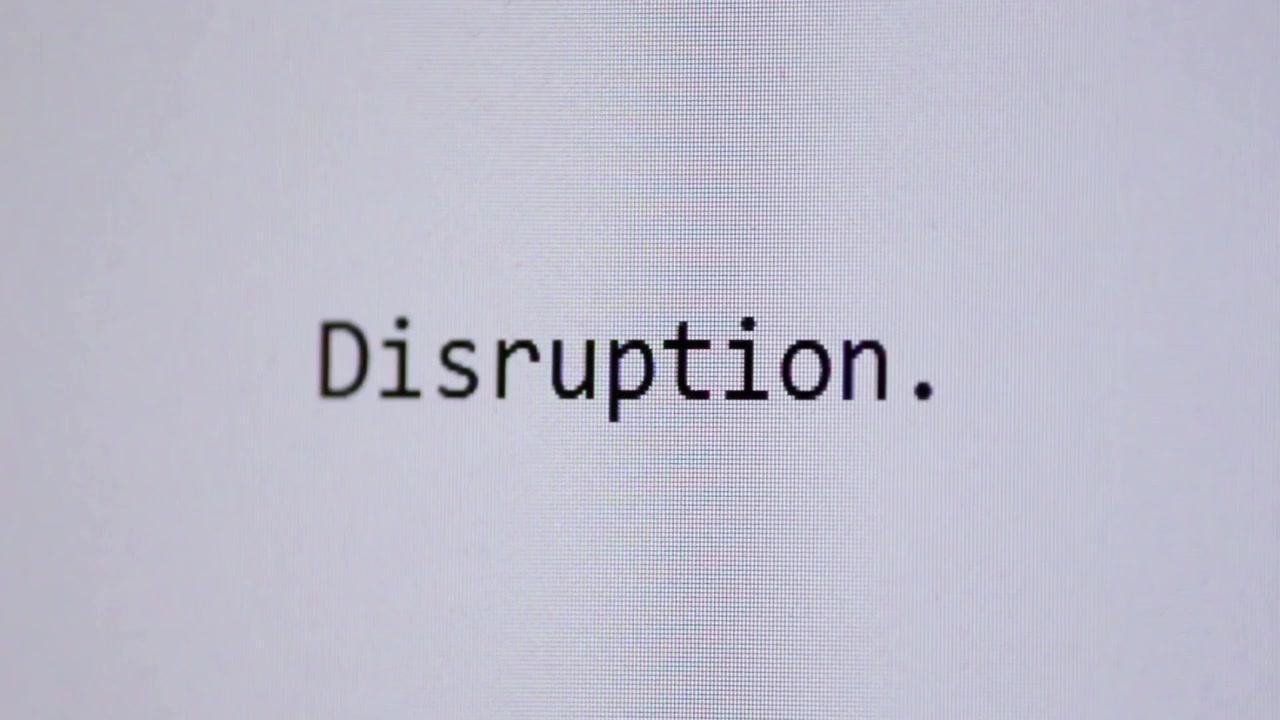 The word “Disruption.” appears as if typed letter by letter on a clean white digital screen, symbolising innovation, change, transformation, technology shifts, and modern business disruption
