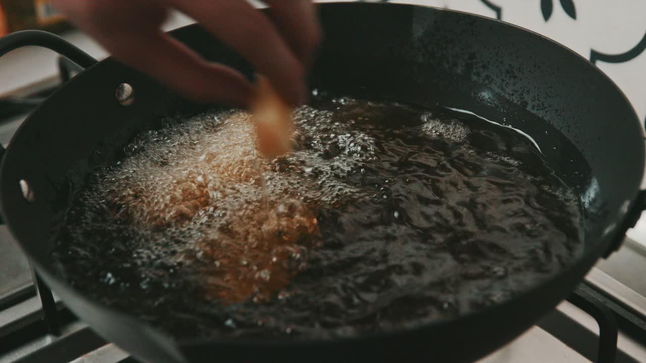 colocando las papas fritas una por una en una sartén con aceite caliente