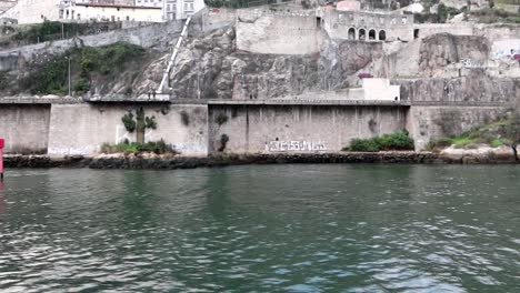 muralha fernandina old walls seen from moving boat over douro river, porto