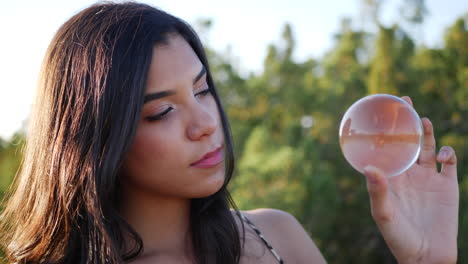 close up of a beautiful woman holding a magical crystal ball in the sunlight of a fantasy world