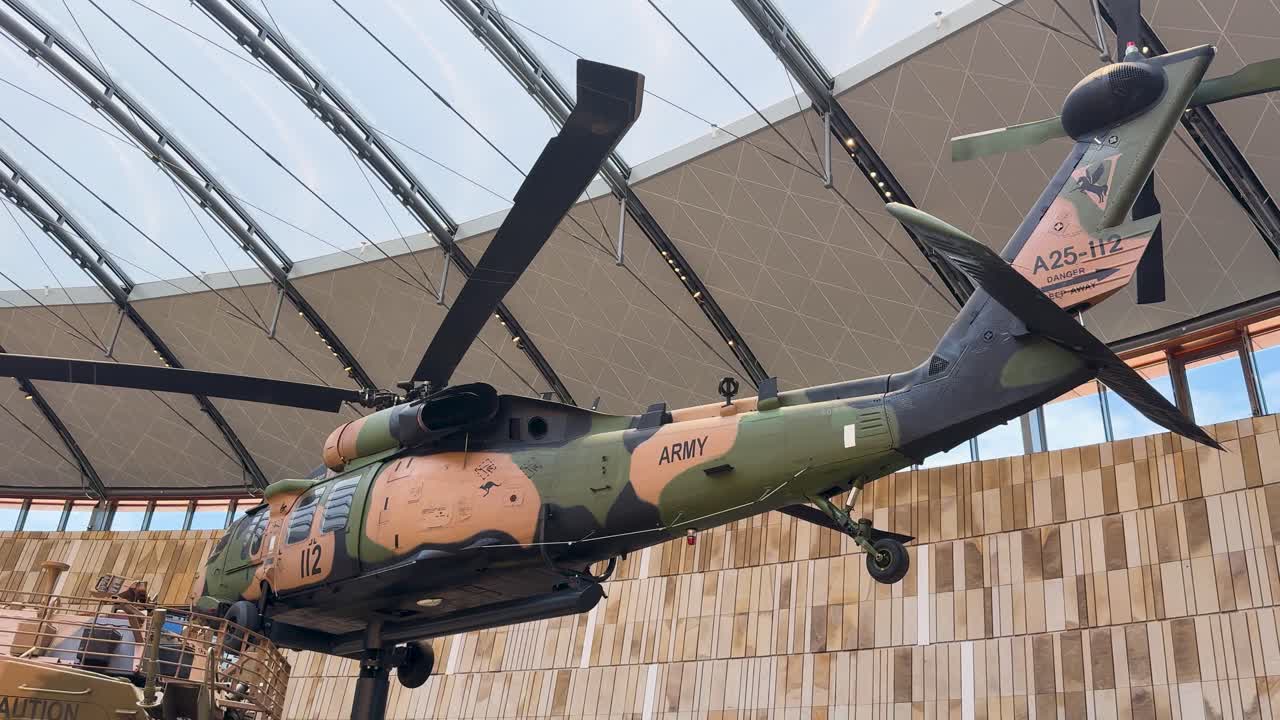 Una lenta panoramica rivela un elicottero militare mimetizzato sospeso sopra un veicolo blindato