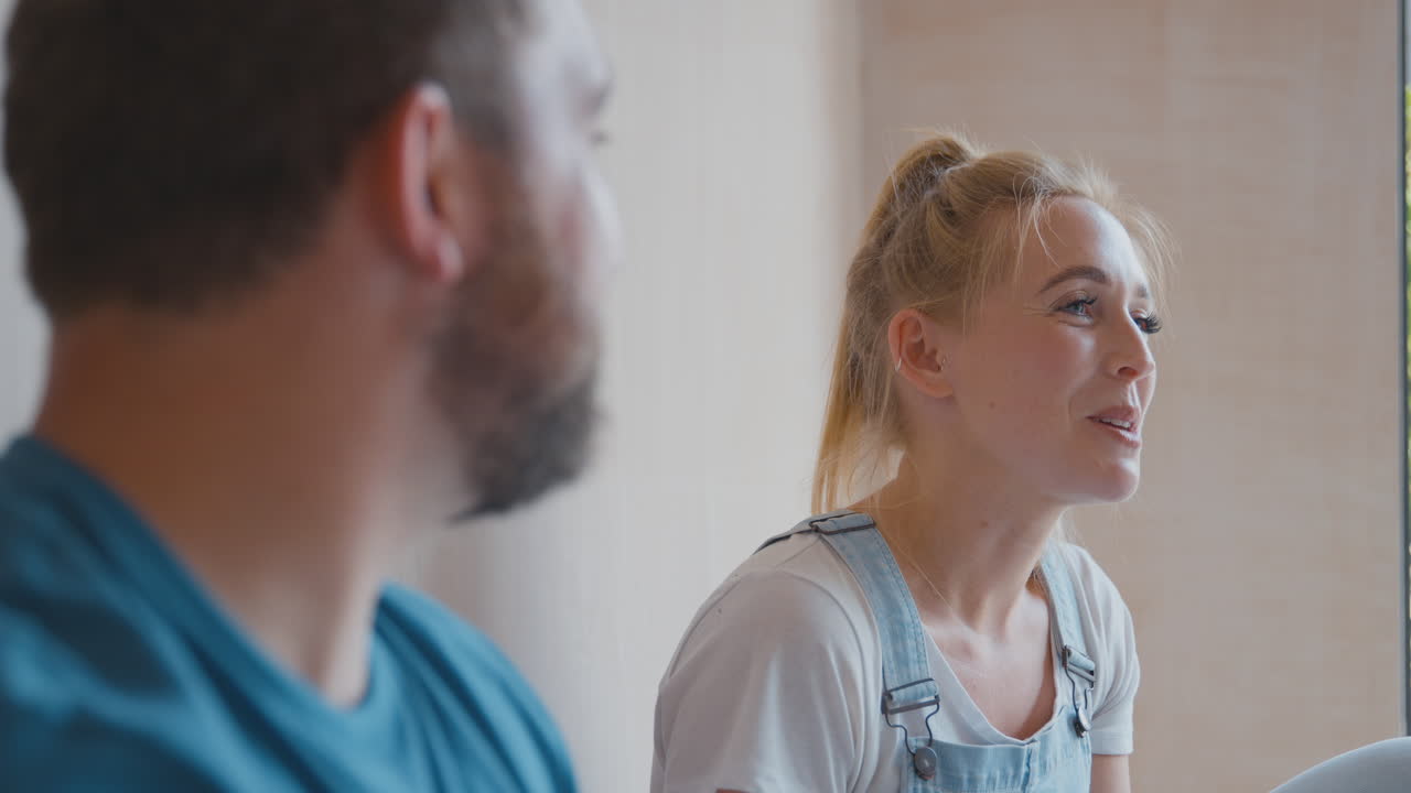 Nærbilde av par som dekorerer rom hjemme, sitter på gulvet og tar en pause med varm drikke