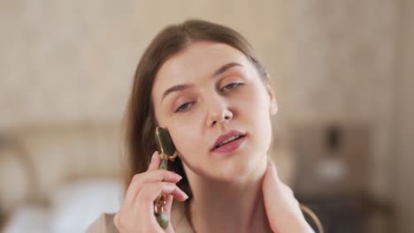 portrait of a young woman doing a facial massage with a jade roller