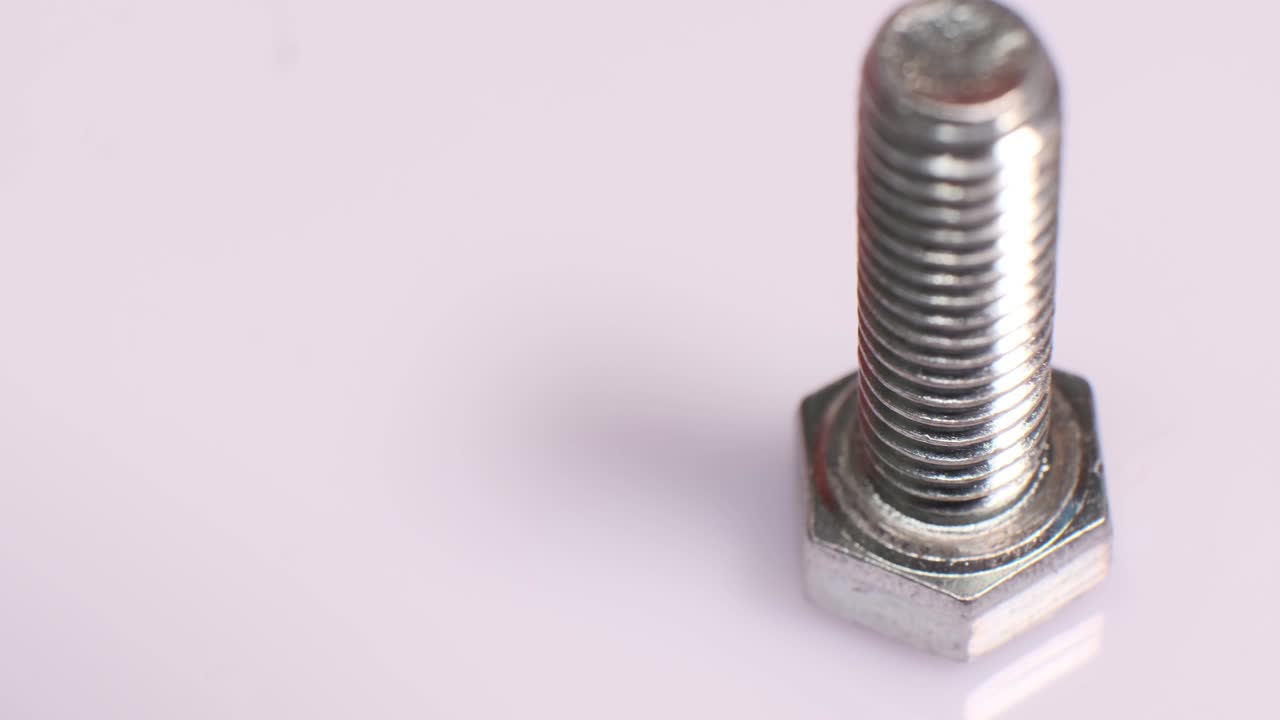 Rotating galvanized metallic screw close-up. Stainless steel bolt isolated on white background. Copy space.