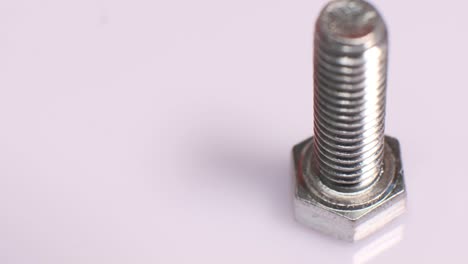rotating galvanized metallic screw close-up. stainless steel bolt isolated on white background. copy space.