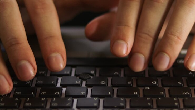 Close up of male hands typing on notebook keyboard front view.