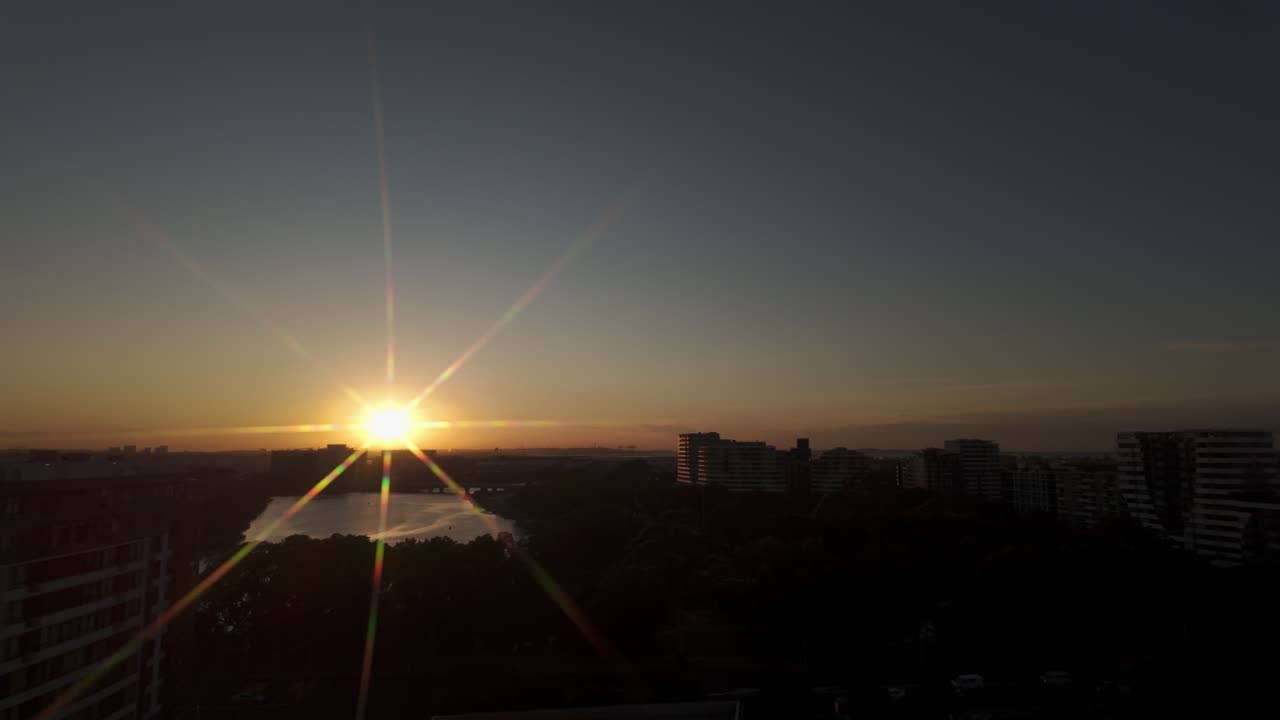 Pôr do sol dourado sobre o horizonte da cidade com reflexo de lente e água