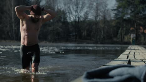 caucasian adult man finishing swim in frozen lake.