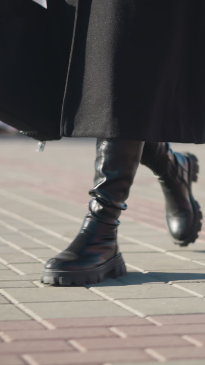 vista lateral de la pierna de una persona con botas negras y abrigo caminando a través de un camino entrelazado, con bicicletas verdes estacionadas y un borrón de edificio urbano en el fondo