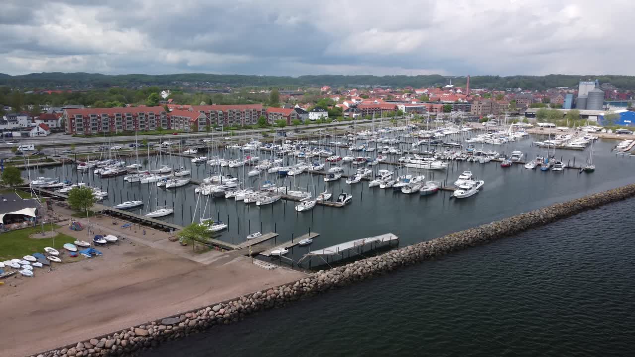 Aabenraa harbor with yachts, residential buildings, and a cloudy sky, aerial view