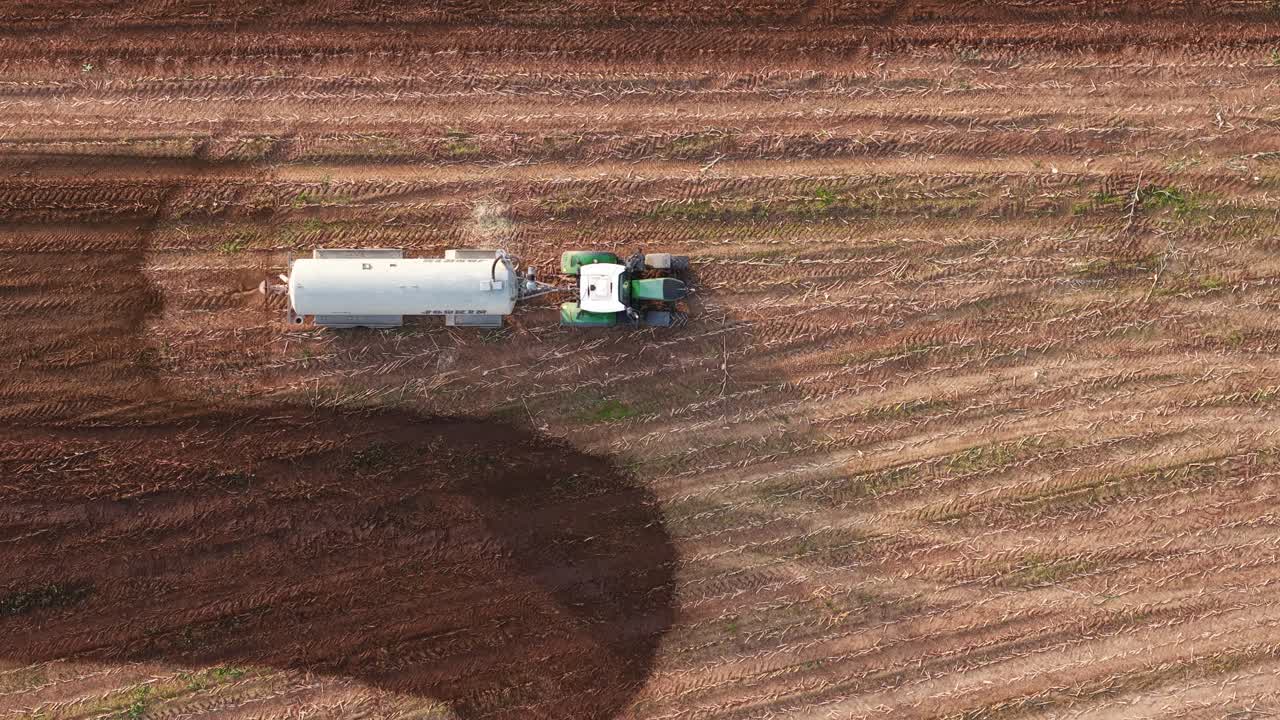 Aerial view of a truck spraying manure on a farmland to fertilize the soil