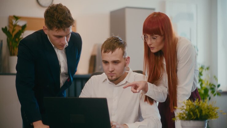 сотрудники планируют на ноутбуке в офисе.