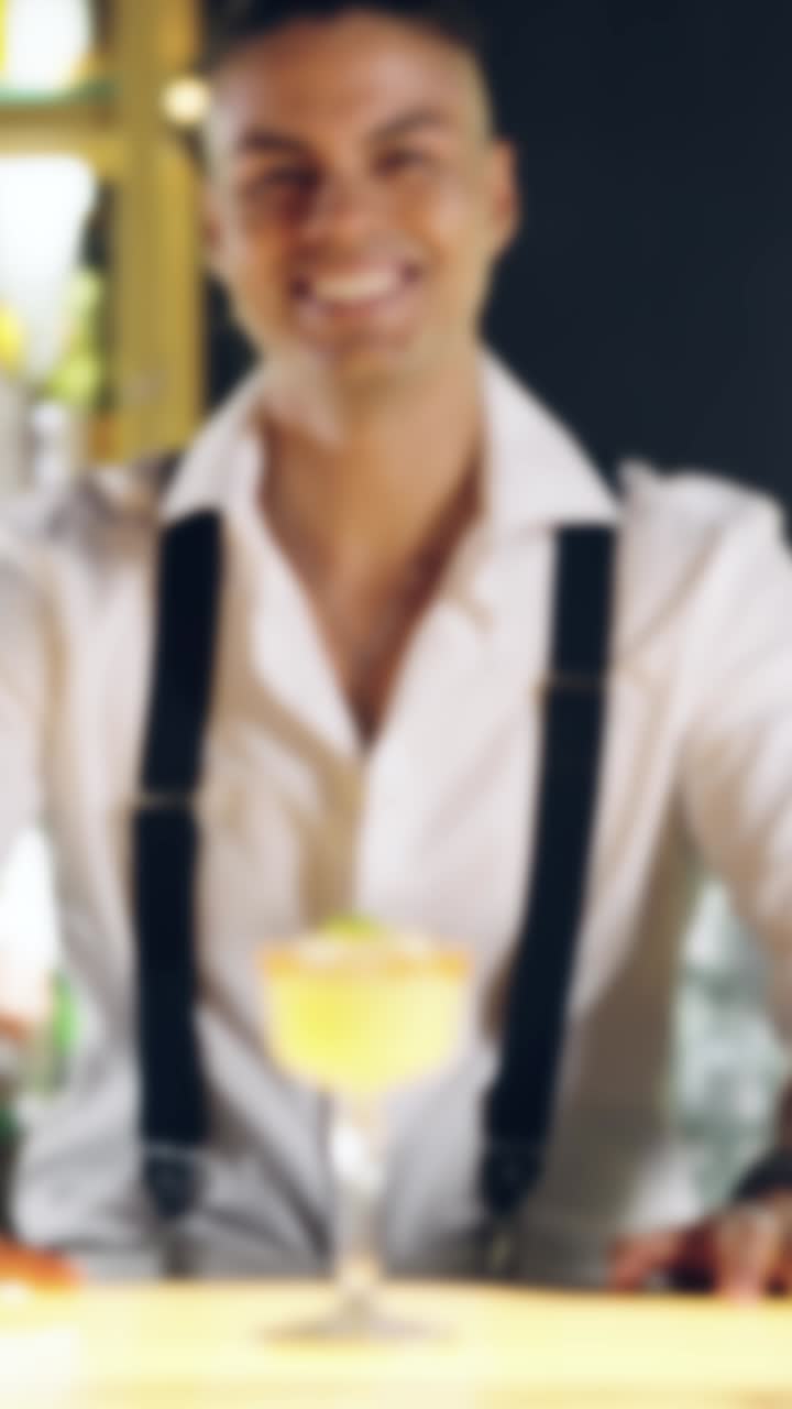 Smiling Bartender Holding a Cocktail Glass at a Bar