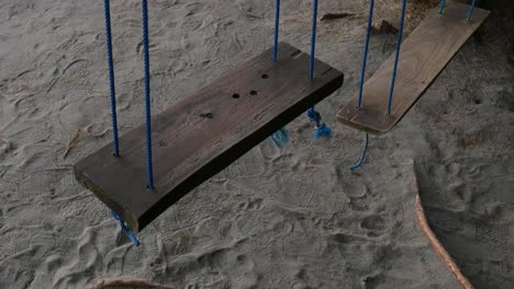 empty swings swaying on playground in the sand dune