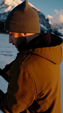 man playing guitar on frozen lake, mountains background