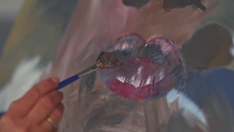 female hands, painting lips with a small painting brush in slow motion