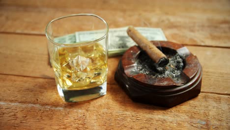 ashtray, cigar, whisky and us dollars on table 4k