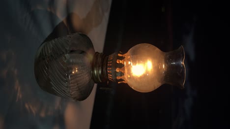 flickering flame in vintage oil lamp casting shadow on table against twilight backdrop