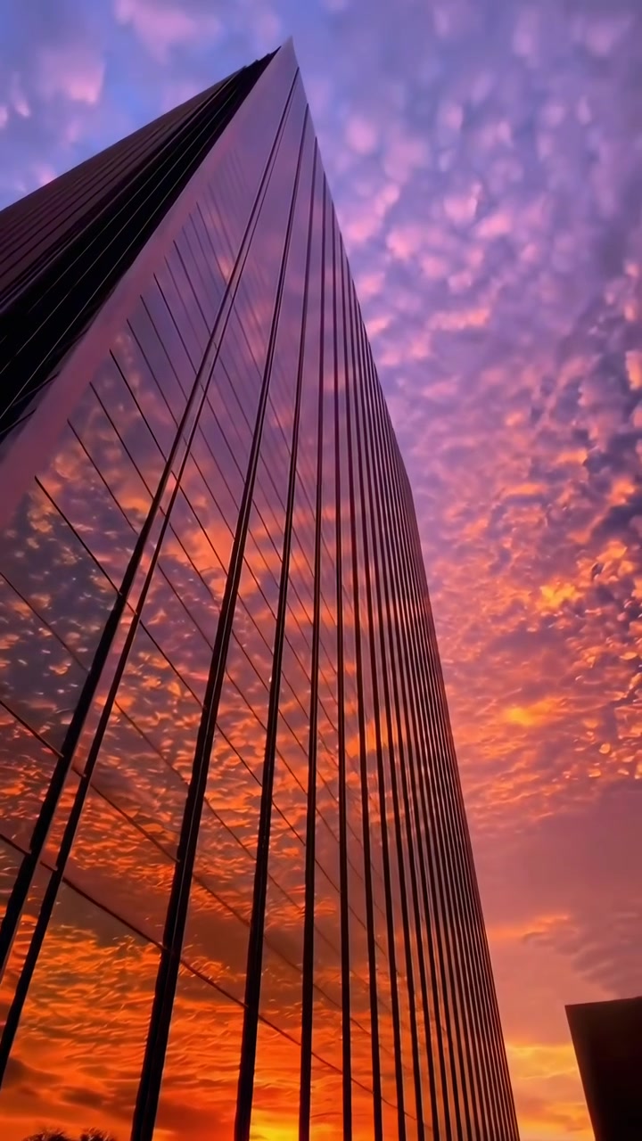 Pôr do sol dramático refletido na fachada de um arranha-céu de vidro moderno