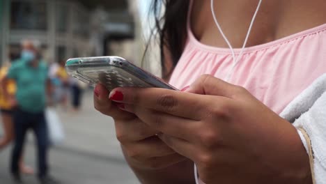 Manos-Femeninas-Enviando-Mensajes-De-Texto-Por-Teléfono-Celular-En-La-Calle,-De-Cerca