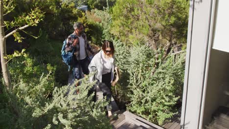 pareja feliz diversa con equipaje y sombreros caminando por las escaleras