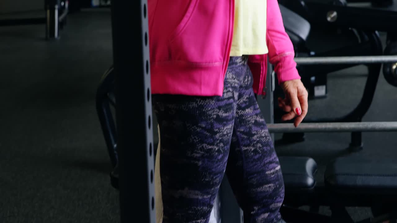 mujer mayor hablando por teléfono móvil en el estudio de fitness 4k