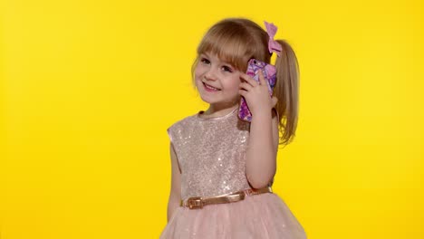 Smiling-kid-girl-5-6-years-old-using-speaking-talking-on-mobile-cell-phone-on-yellow-background