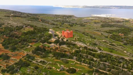 Drone-shot-ziplining-towards-Mellieha's-Red-Tower,-also-known-as-St-Agatha's-Tower