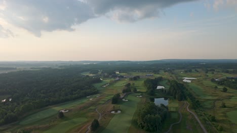 drone over lush golf course fairway surrounded by trees on sunny summer day