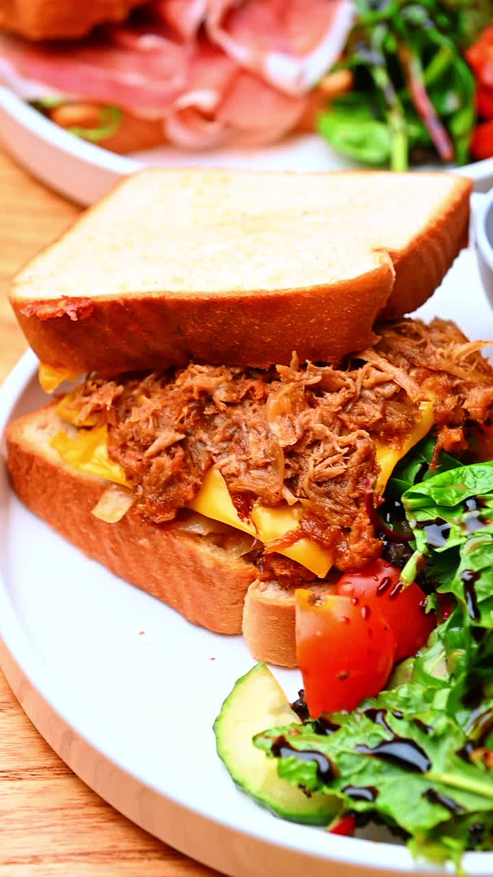 Panino con carne sfilacciata e verdure. Pane tostato ripieno di carne sfilacciata, formaggio e insalata conditi con salsa