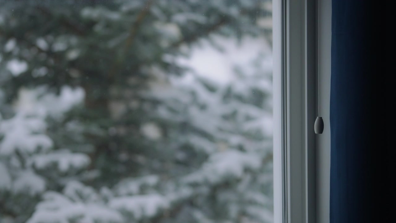 Snow falling outside the window in winter.