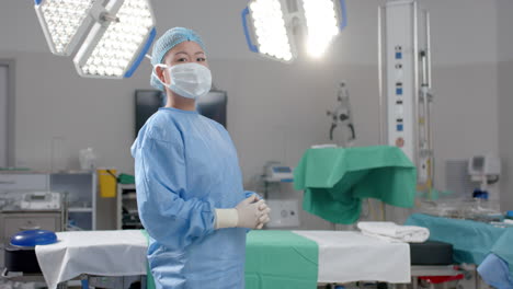 una joven asiática se para con confianza en una sala de cirugía de un hospital con espacio para copiar