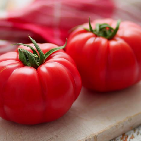 Two-fresh-eco-tomatoes-placed-on-white-wooden-cutting-board--Healthy-food-concept