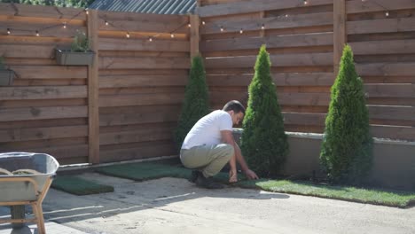 jardinero colocando césped en el patio privado con valla de madera