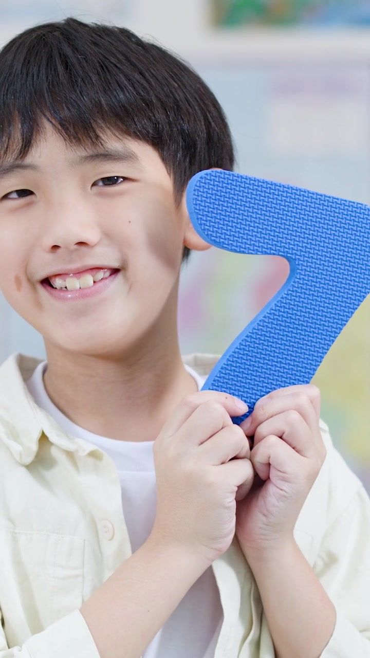 Happy Asian Boy Holds Blue Number Seven for Learning