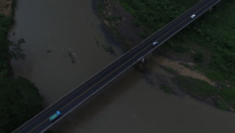 descending aerial as cars move across costa rica crocodile bridge over river, 4k