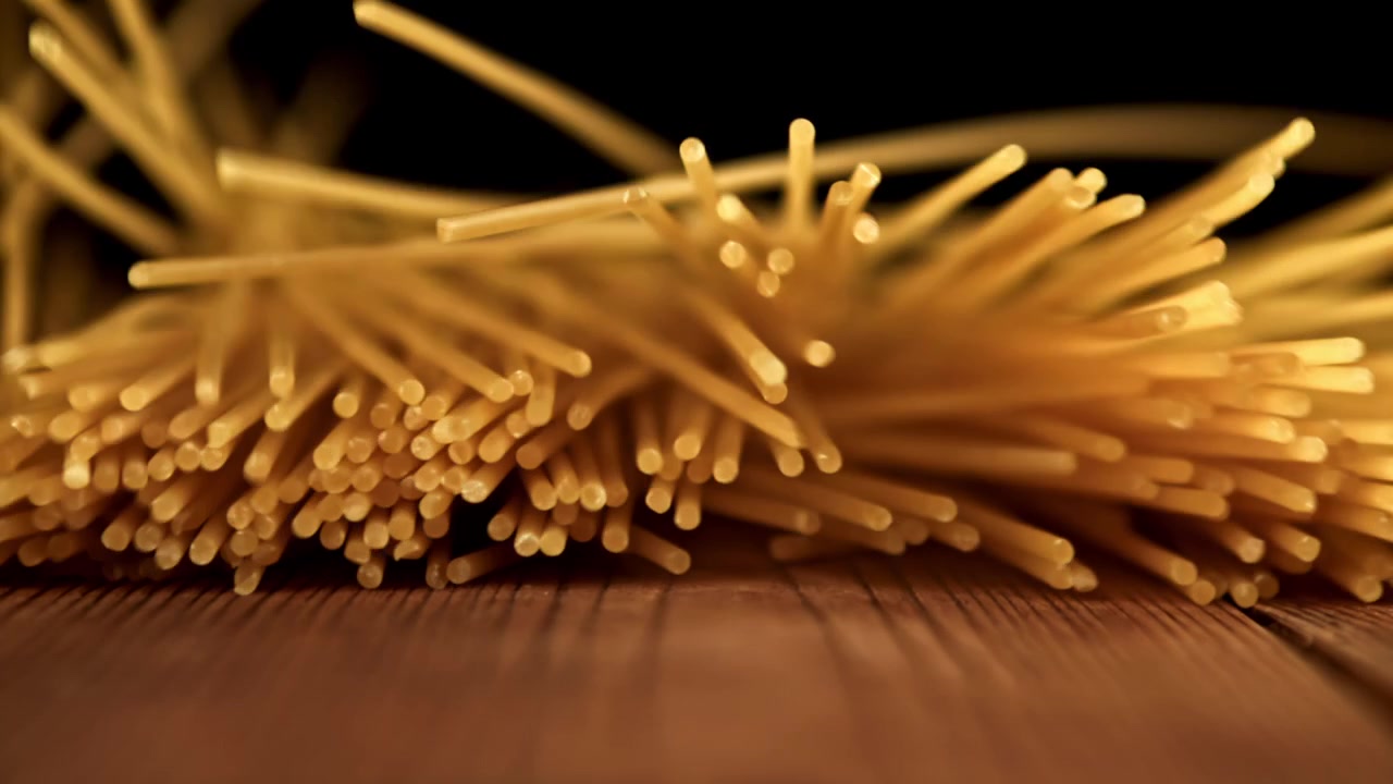 Spaghetti dorati che cadono al rallentatore su un tavolo di legno