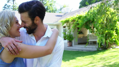 pareja linda sonriendo y sosteniéndose el uno al otro frente a una casa