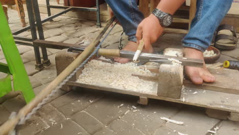 a scene of a man hand-shaping wood with a chisel on a manual lathe in marrakech, morocco - close up