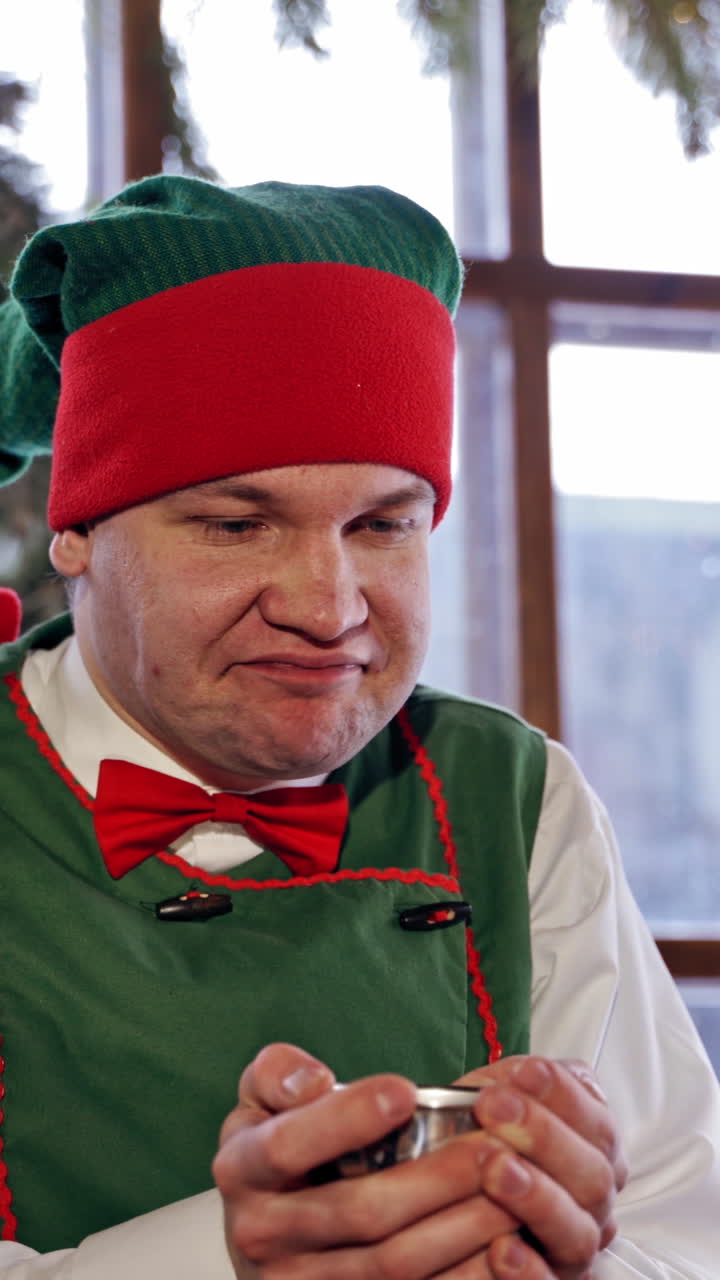 Elf drinking tea at a table. Santas elf drinking Christmas tea in a decorated room. Closeup. Vertical video