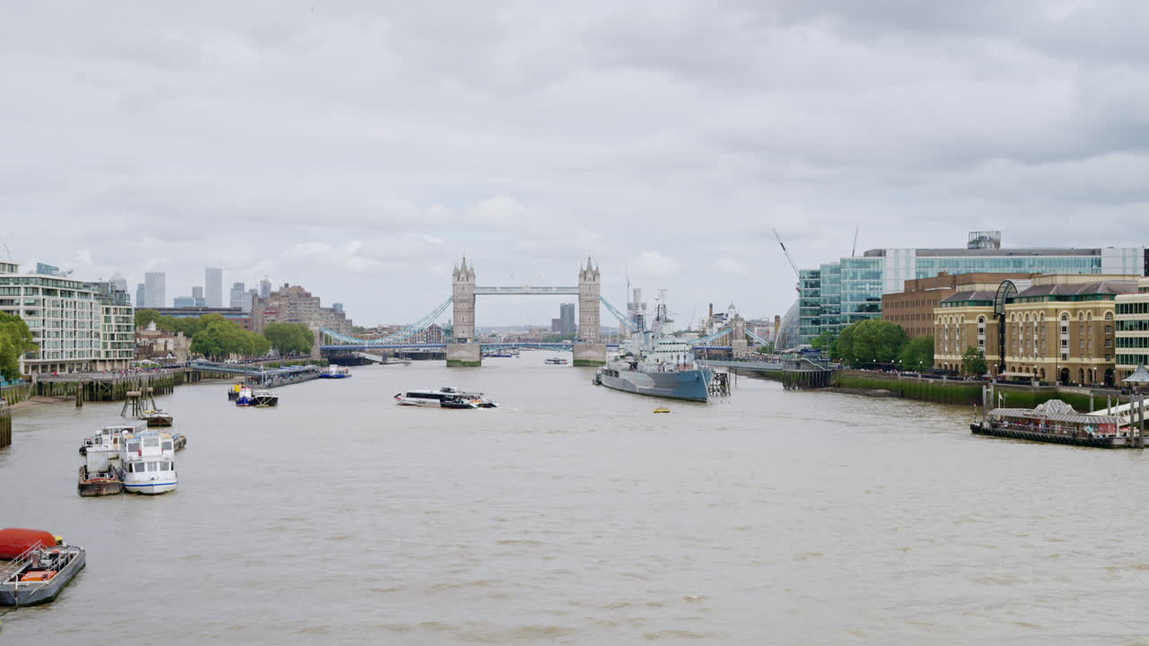 View of the Thames river in London downtown, United Kingdom. Tower Bridge in the distance, moored HMS Belfast museum ship and other moored and floating boats