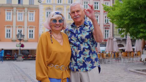 elderly stylish couple tourists man woman looking approvingly at camera showing ok gesture like sign