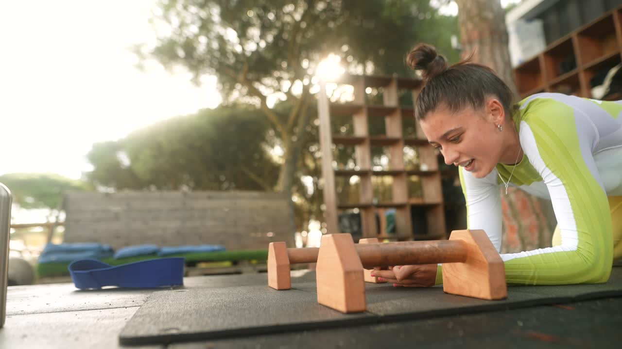 Giovane donna che si allena con le parallele in una palestra all'aperto