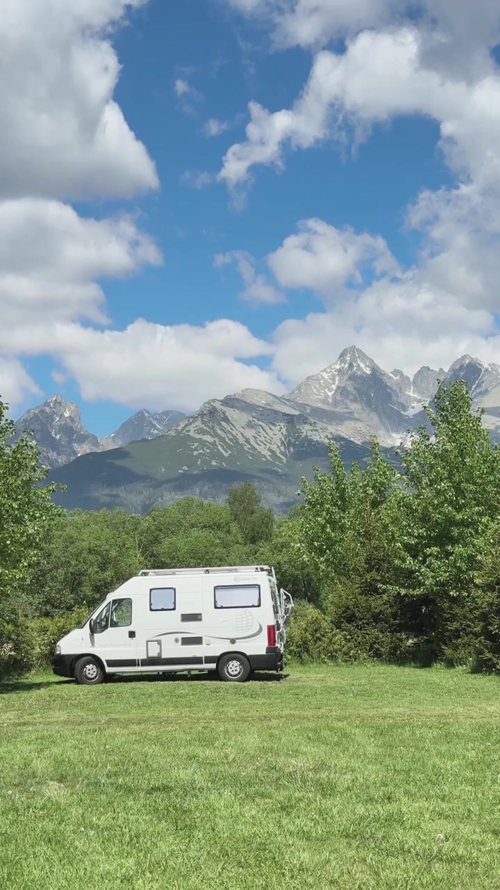 A campervan stands on a camping ground in Slovakia as the camera pans upward to reveal the scenic Tatra Mountains beyond.