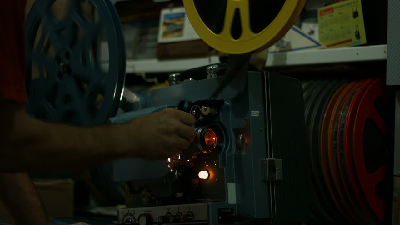 Primo piano di una mano che aziona un proiettore cinematografico d'epoca