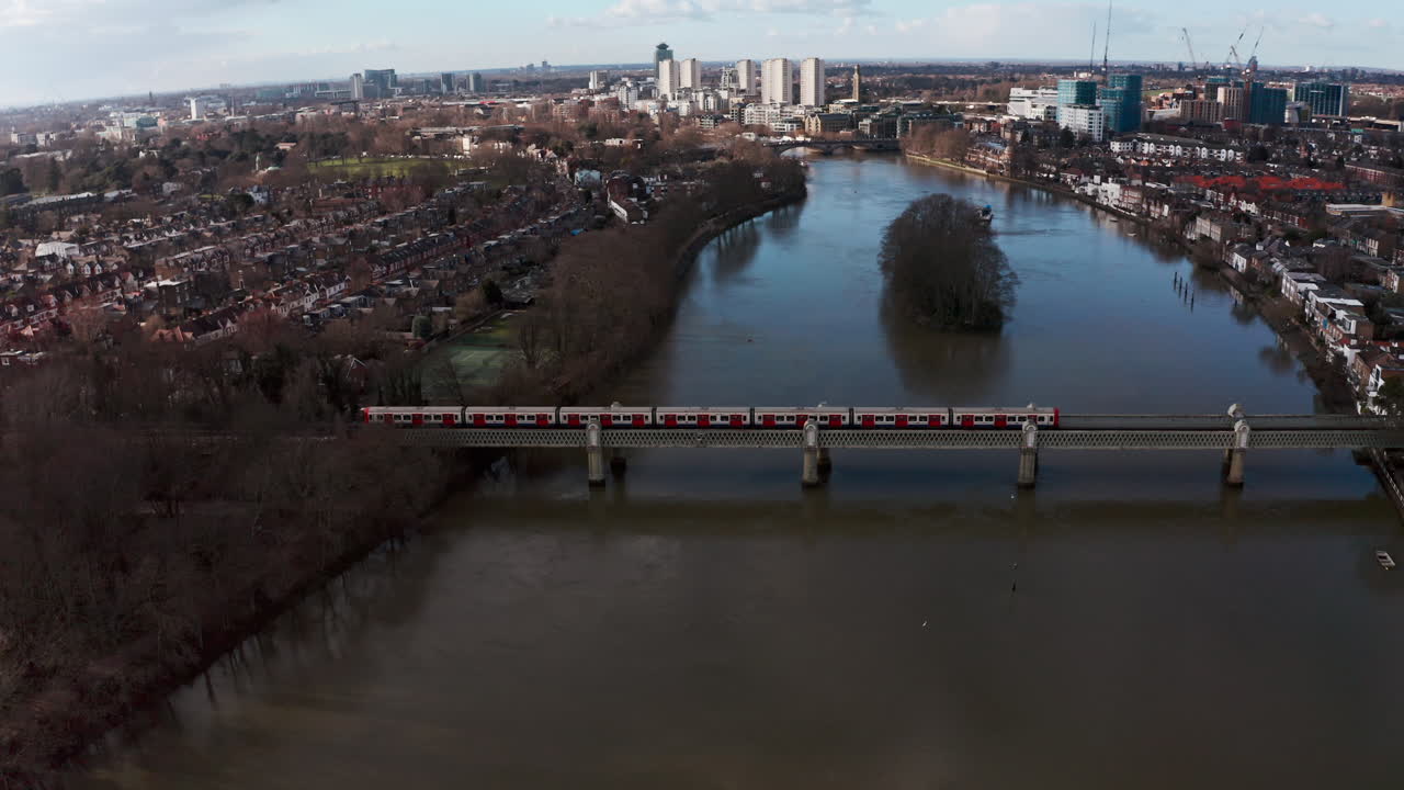 toma cinematográfica de un dron giratorio del tren de la línea del distrito de londres en el puente ferroviario de kew