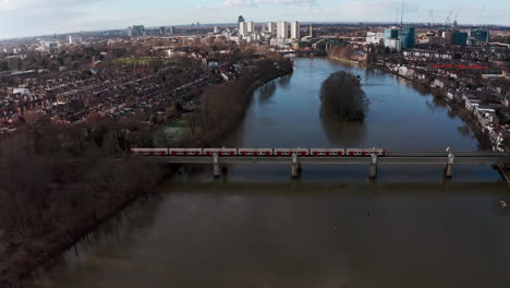 cinematic rotating drone shot of london district line train on kew railway bridge